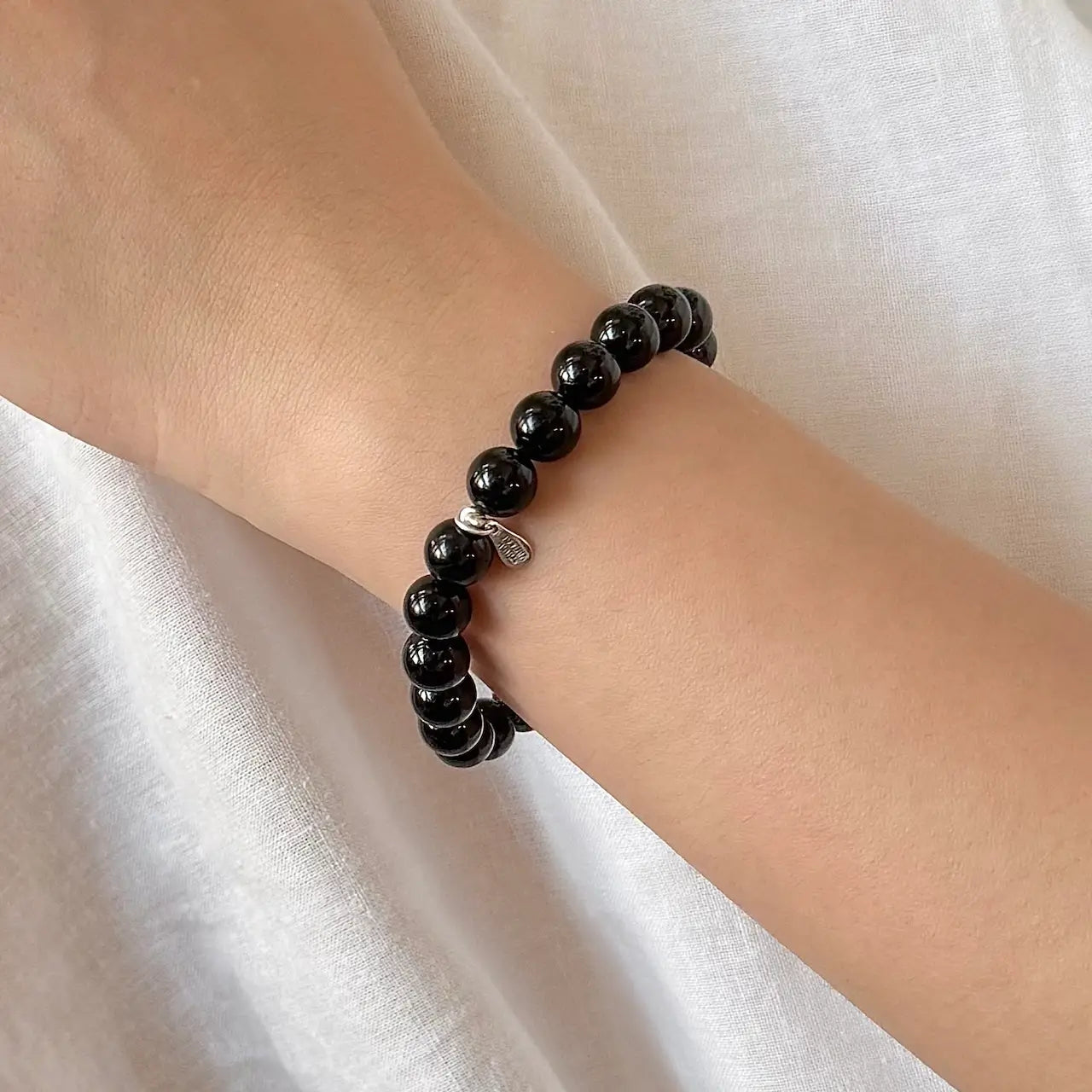Black tourmaline bracelet on wrist for grounding, protection, and energy balance